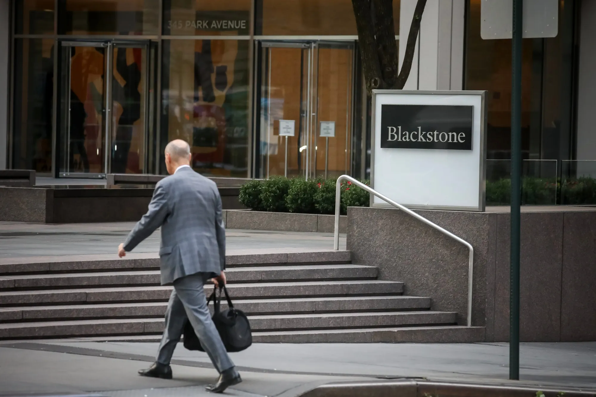 A man walking past Blackstone's headquarters sign at 345 Park Avenue