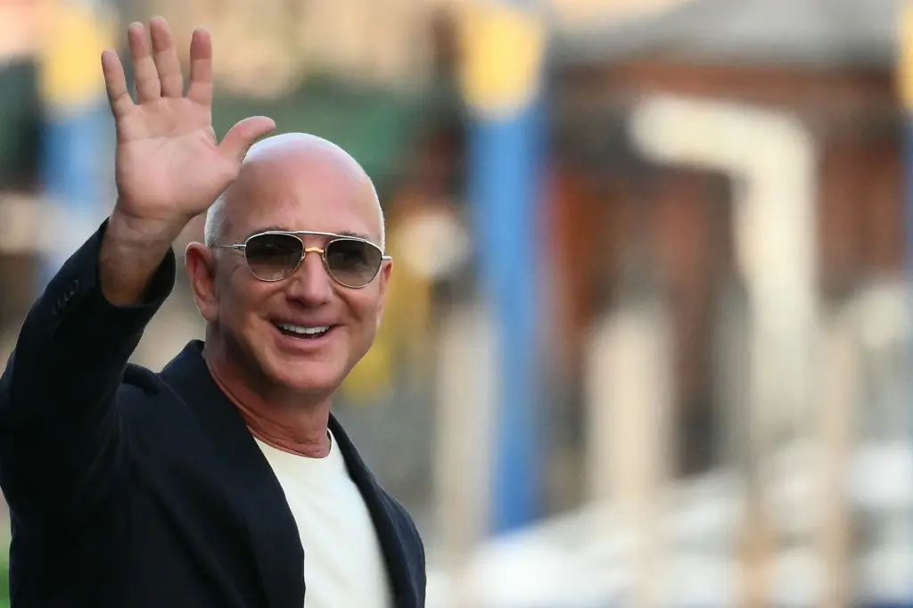 Jeff Bezos waving while wearing sunglasses and a dark blazer