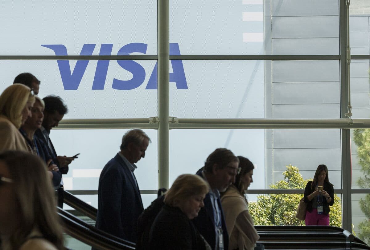 People walking past the Visa logo at a company office